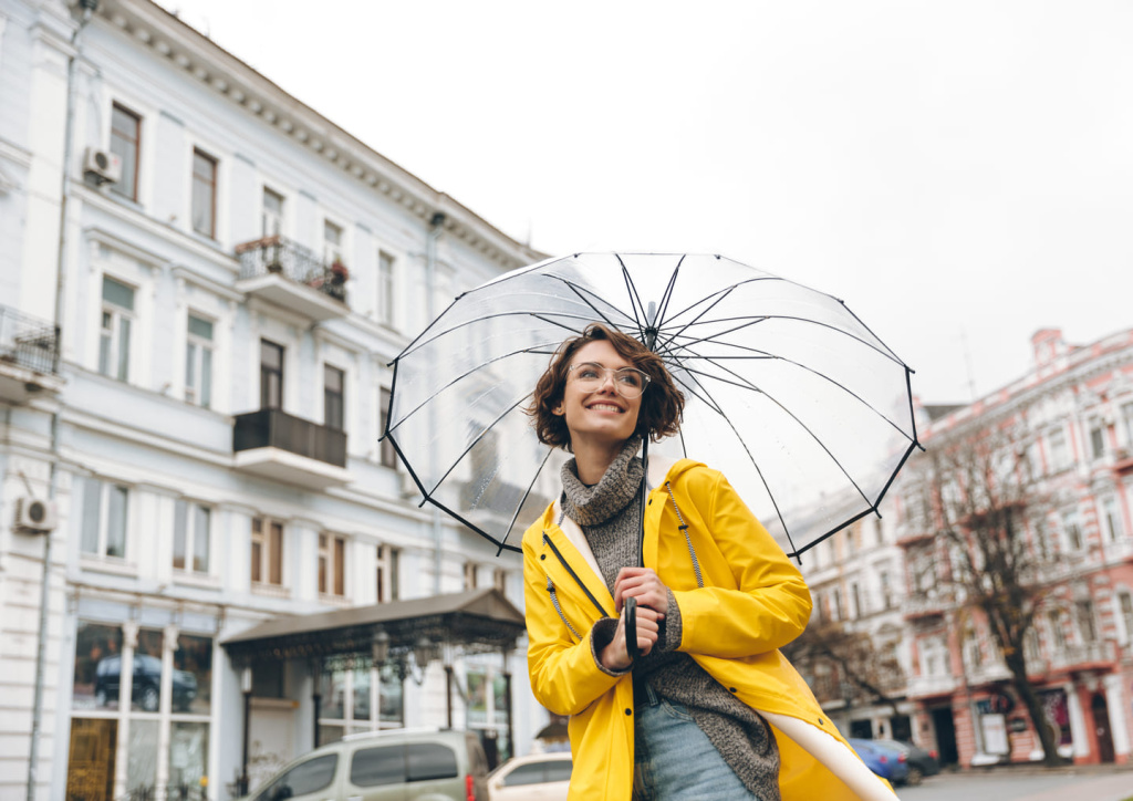 optimistic-woman-yellow-raincoat-glasses-having-fun-while-walking-through-city-big-transparent-umbrella-cold-rainy-day.jpg